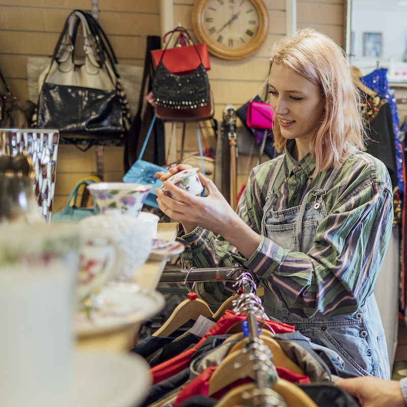 A woman looks at a vintage porcelain trinket inside a consignment store.